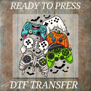 May include: A DTF transfer design featuring five video game controllers styled as Halloween characters: a blue zombie controller, a white ghost controller, an orange pumpkin controller, a green Frankenstein controller, and a white mummy controller.