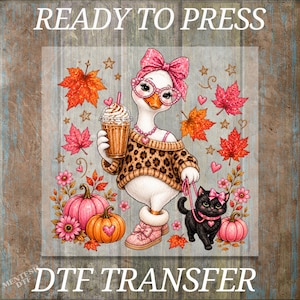 May include: A DTF transfer design featuring a white goose wearing a leopard print sweater, pink glasses, and a pink bow, holding a coffee cup and a leash attached to a black kitten. The scene includes orange maple leaves, pink pumpkins, and stars.