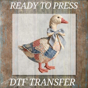 May include: A stuffed goose with a patchwork design in red, white, and blue fabrics. The goose has a checkered bow and a red and white checkered beak and feet. The text "READY TO PRESS" and "DTF TRANSFER" are displayed.