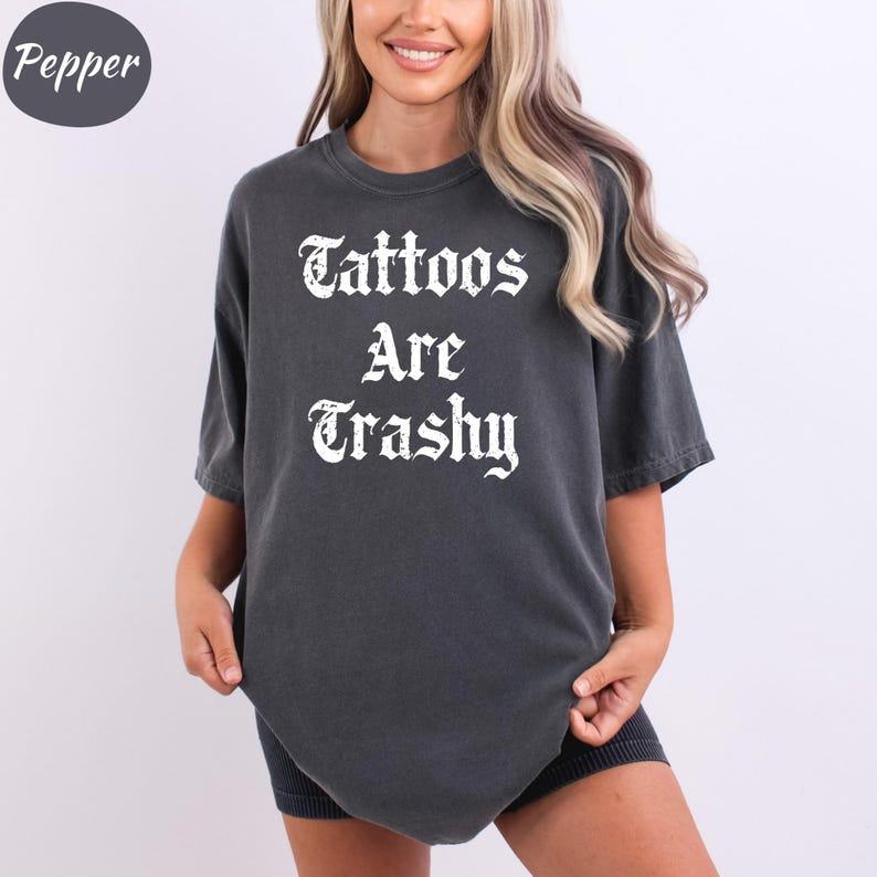 a woman wearing a black shirt that says tattoos are grasy