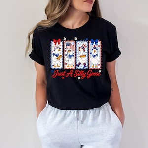 A woman wearing a black t-shirt with a graphic design featuring four cartoon ducks in patriotic colors and accessories.