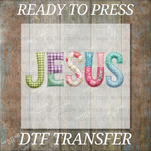 May include: A colorful DTF transfer featuring the word "JESUS" in a patchwork design. The letters are filled with various patterns, including gingham, floral, and polka dots. The text "READY TO PRESS" and "DTF TRANSFER" are displayed.