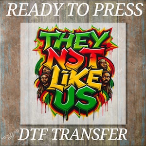 May include: A colorful DTF transfer design with the text "THEY NOT LIKE US" in bold, graffiti-style lettering. The design features red, yellow, green, and black colors, with images of people with dreadlocks. The words "READY TO PRESS" and "DTF TRANSFER" are also visible.