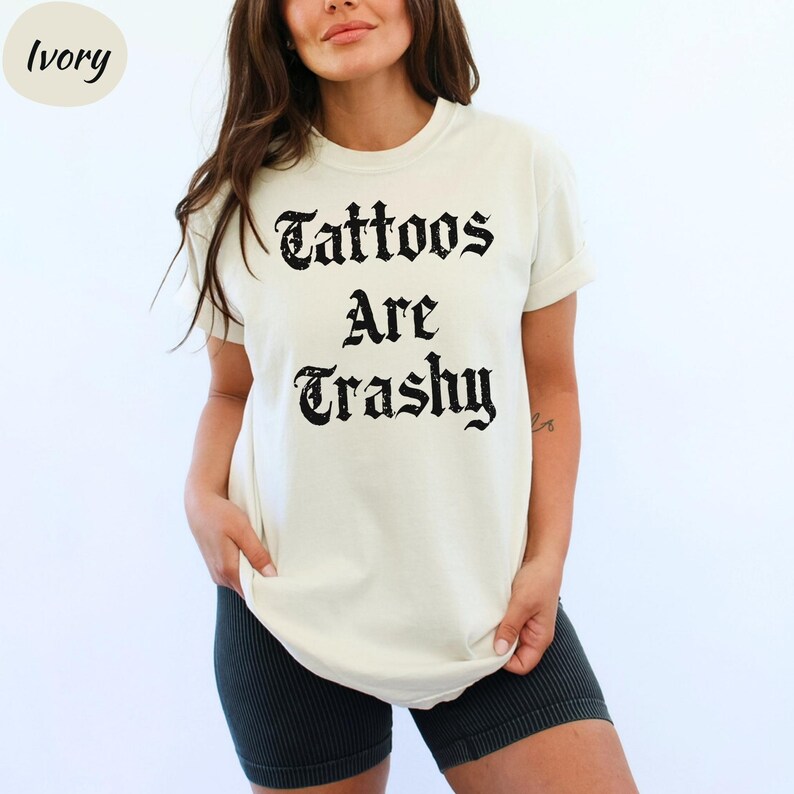a woman wearing a t - shirt that says tattoos are trashy