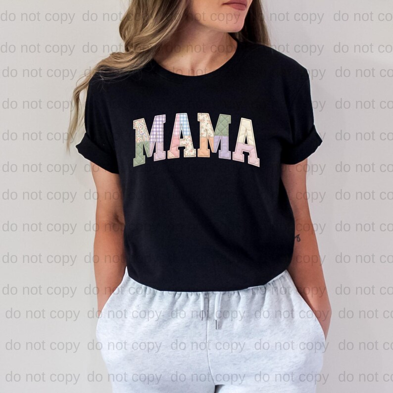 A woman wearing a black t-shirt with the word "MAMA" printed on it, standing against a plain background.