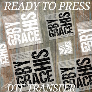 May include: A set of six iron-on transfers with the phrase "By His Grace" and the Bible verse "Romans 3:23-24". The transfers are printed in black and white on a clear background.