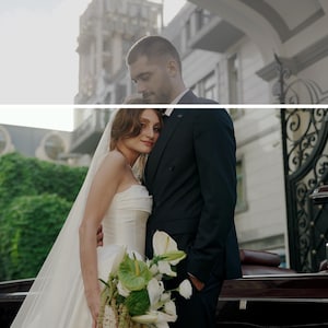 Pode incluir: Um casal recém-casado posa para uma foto ao ar livre. A noiva usa um vestido de noiva branco sem alças e véu, segurando um buquê. O noivo está de terno preto. Um carro bordô clássico está estacionado por perto.