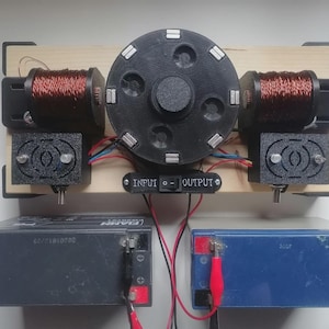May include: An electrical device with a central black circular component and silver accents, copper coils, and a switch labelled "INPUT" and "OUTPUT". It is connected to a black and a blue battery. The device is mounted on a wooden base.
