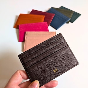 Hand holding brown cardholder wallet.