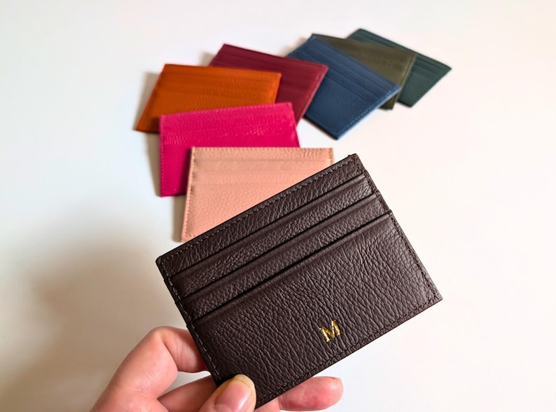 Hand holding brown cardholder wallet.