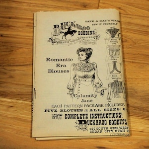 May include: Vintage sewing pattern booklet for Romantic Era Blouses by Buckaroo Bobbins. The cover features an illustration of a woman in a blouse, with text including "Calamity Jane" and "Complete Instructions!"