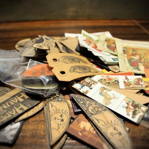 May include: A collection of assorted craft supplies, including tags with eye illustrations, tags with the text "HAPPY HAUNTING", and small, colorful illustrations. Some items are in a clear plastic bag.
