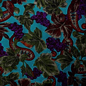 May include: A teal fabric with a repeating pattern of grapes, leaves, and paisley designs. The grapes are purple, the leaves are green and burgundy, and the paisley elements feature red, orange, and white details.