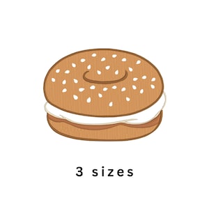 Peut inclure: Un écusson brodé en forme de bagel avec une surface dorée grillée parsemée de graines de sésame blanches, un trou central et une épaisse couche de fromage à la crème blanc au milieu. Le texte 3 sizes est imprimé en noir sous le bagel.