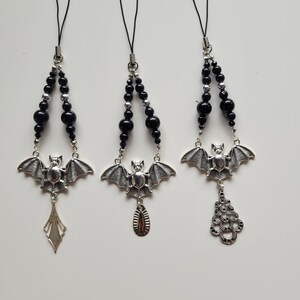 May include: Three black and silver beaded phone charms with bat pendants. Each charm has a different silver pendant: a diamond shape, a teardrop, and a filigree design.