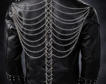 May include: A black leather jacket featuring silver-toned metal studs along the collar and cuffs. The back is decorated with a vertical central lacing system made of silver chains, flanked by multiple draped silver chain strands on each side.