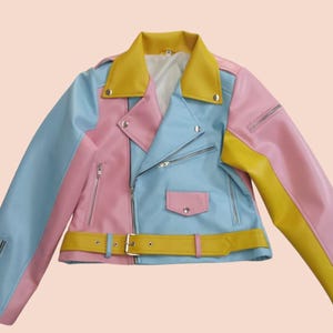 Può includere: Una giacca di pelle color pastello con uno schema di colori blu, rosa e giallo. La giacca ha una chiusura a zip, una cintura e due tasche.