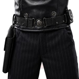 May include: A black faux leather waistcoat with silver buttons worn over black pinstriped trousers. A black utility belt with a central circular buckle, metal hardware, and a side pouch is fastened around the waist, with a holster attached to the right side.