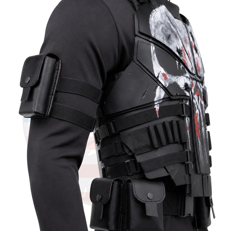 May include: Black tactical vest with a white skull design and red accents. The vest features multiple pouches and straps, along with a black arm pouch. This item is suitable for cosplay or costume use.