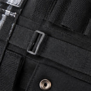 May include: Close-up of a black bag or backpack with a textured fabric. The image highlights the details of the straps, a buckle, and a metal snap closure. The design suggests a durable and functional accessory.