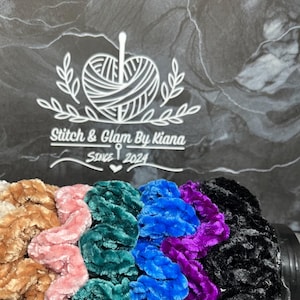 Op de afbeelding: Een set van zes kleurrijke scrunchies gemaakt van fluweel. De scrunchies zijn gestapeld, met de kleuren van boven naar beneden beige, bruin, roze, teal, blauw, paars en zwart.