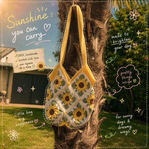 Op de afbeelding: Een geel en witte gehaakte draagtas met een zonnebloemmotief gemaakt van individuele vierkantjes. De tas heeft een lange schouderband en is versierd met teksten waaronder Sunshine you can carry, 100% handmade en Little bag big happiness.