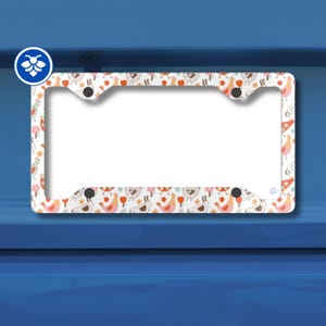 Può includere: Cornice bianca per targa con un motivo ripetuto di uccelli colorati, fiori e altri elementi decorativi. La cornice ha uno sfondo bianco e un bordo blu. La cornice è in metallo e ha quattro fori di montaggio.