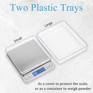 May include: A digital scale with a clear plastic tray, showing "30.00" on its screen, beside a larger, empty tray. The text reads "Two Plastic Trays" and "As a cover to protect the scale, or as a container to weigh powder."