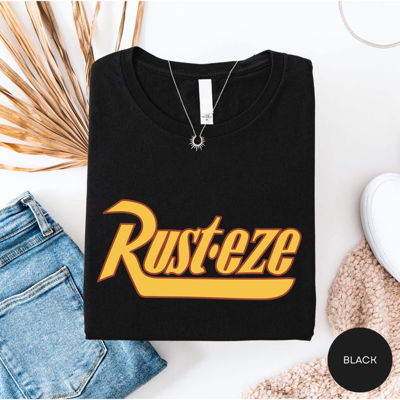 a black t-shirt with a yellow and orange graphic design, a pair of blue jeans, and some accessories such as a necklace and a white object.