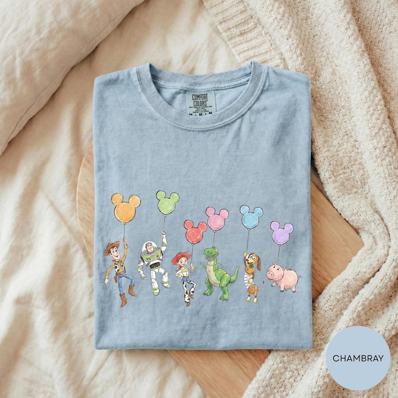 A t-shirt with a graphic design featuring characters from the Toy Story movie, including Woody, Buzz Lightyear, and other beloved characters, along with various Disney-themed characters such as Mickey Mouse and Minnie Mouse.