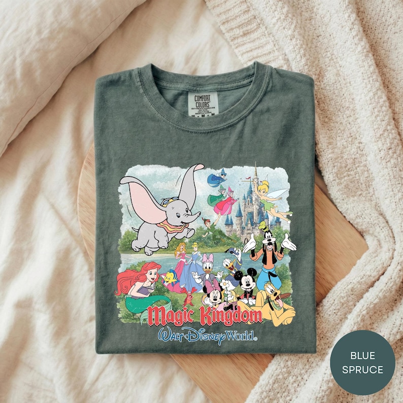 A t-shirt with a colorful graphic design featuring characters from Disney's Magic Kingdom, including elephants, fairies, and other iconic figures.