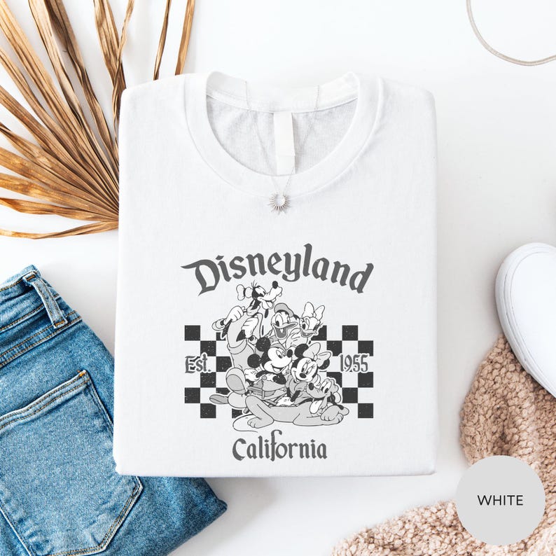 a white t-shirt with a graphic design of Disney characters and text, along with a pair of jeans and a white scarf.
