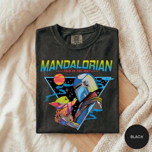A black t-shirt with a graphic design featuring the characters Yoda and the alien Zorlax from the Star Wars series, along with a space scene.