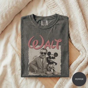 A gray t-shirt with a graphic design featuring a man and a character from Disney, specifically Mickey Mouse.