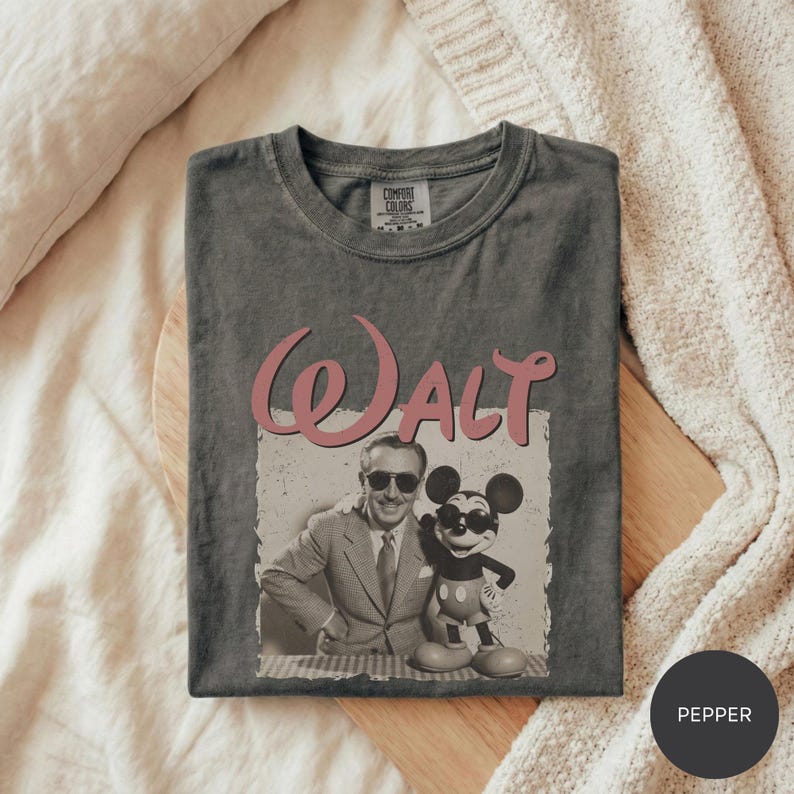 A gray t-shirt with a graphic design featuring a man and a character from Disney, specifically Mickey Mouse.