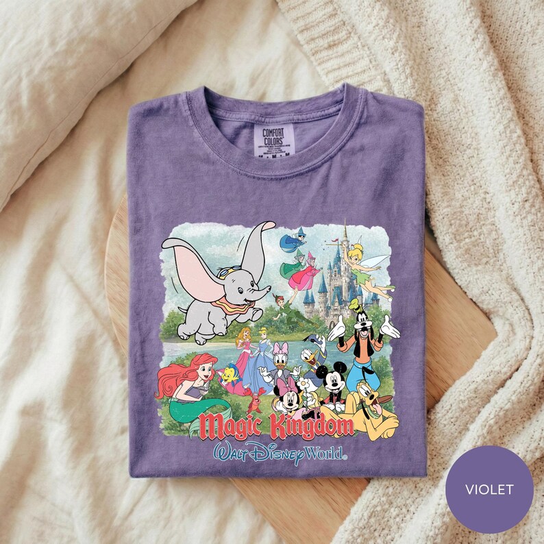 A purple t-shirt with a colorful graphic design depicting various Disney characters and a castle, along with the text "Magic Kingdom Walt Disney World."