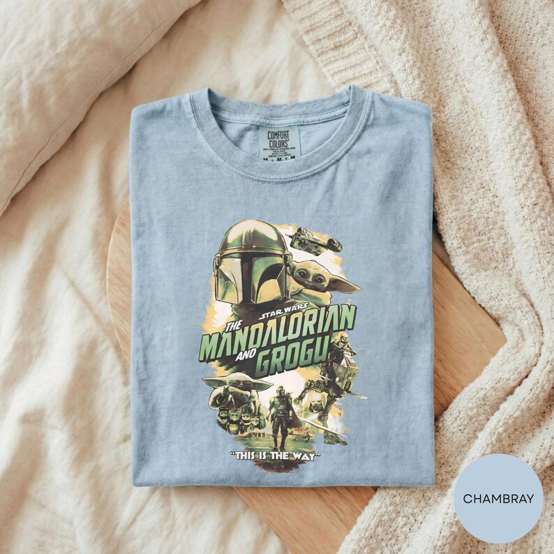 A t-shirt with a graphic design featuring characters from the Star Wars series, specifically The Mandalorian and the Frogs.