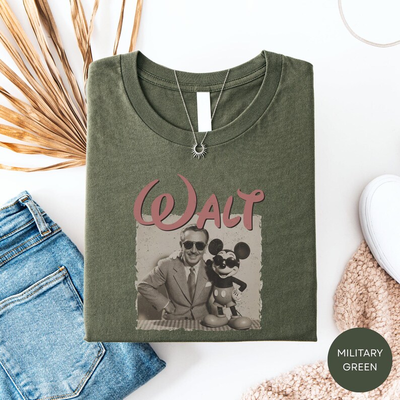 a green t-shirt with a graphic of Walt Disney and Mickey Mouse, along with a necklace and a pair of jeans.