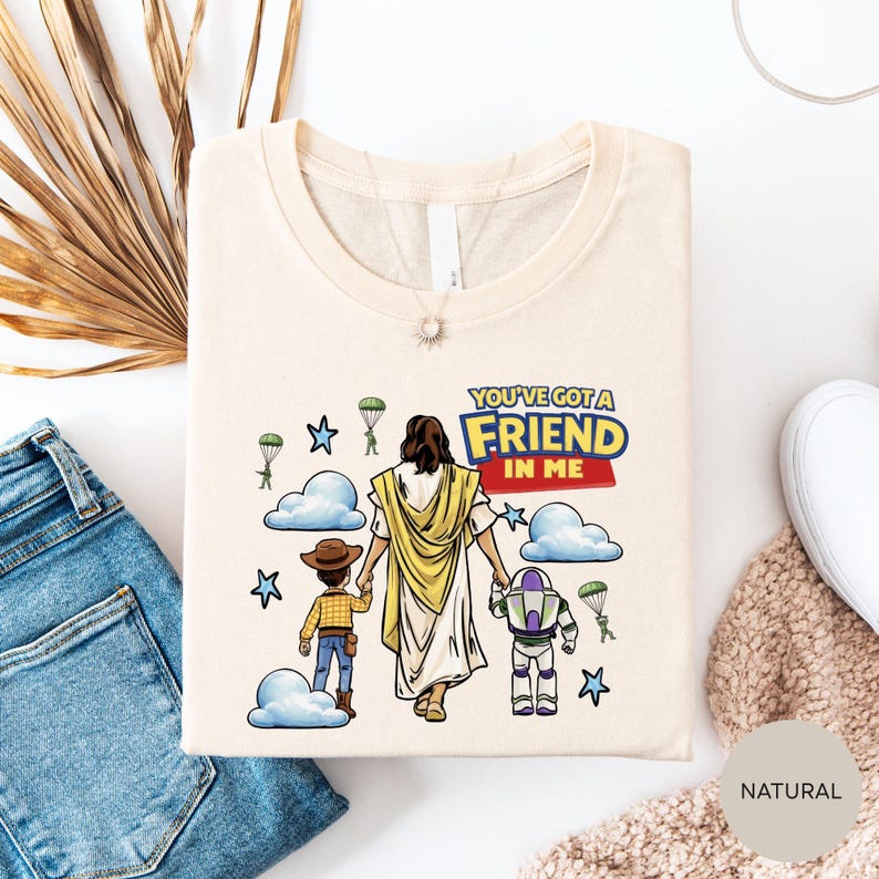 a t-shirt with a cartoon illustration of a person holding hands with two children, one of whom is a robot. The t-shirt has a message that says "You've got a friend in me".