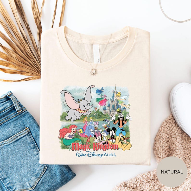 A t-shirt featuring a colorful illustration of Disney characters from the "Magic Kingdom" theme park, along with the text "Magic Kingdom Walt Disney World".