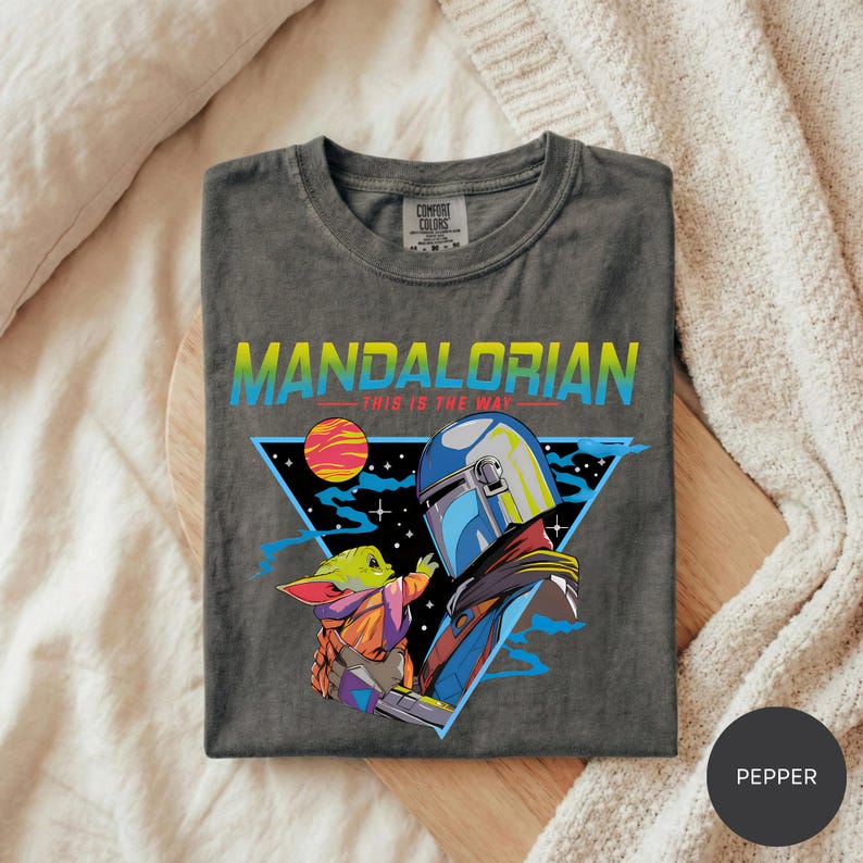 A gray t-shirt with a graphic design featuring a young alien character and a human character in a space-themed setting.