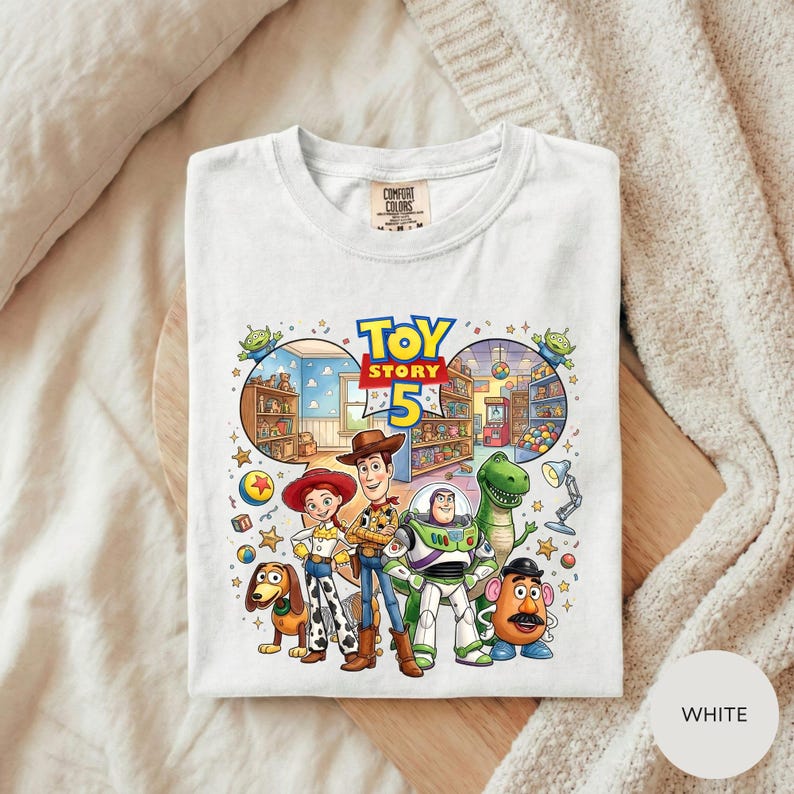 A white t-shirt with a colorful illustration of characters from the Toy Story movie, including Woody, Buzz Lightyear, Timmy, and other beloved characters.