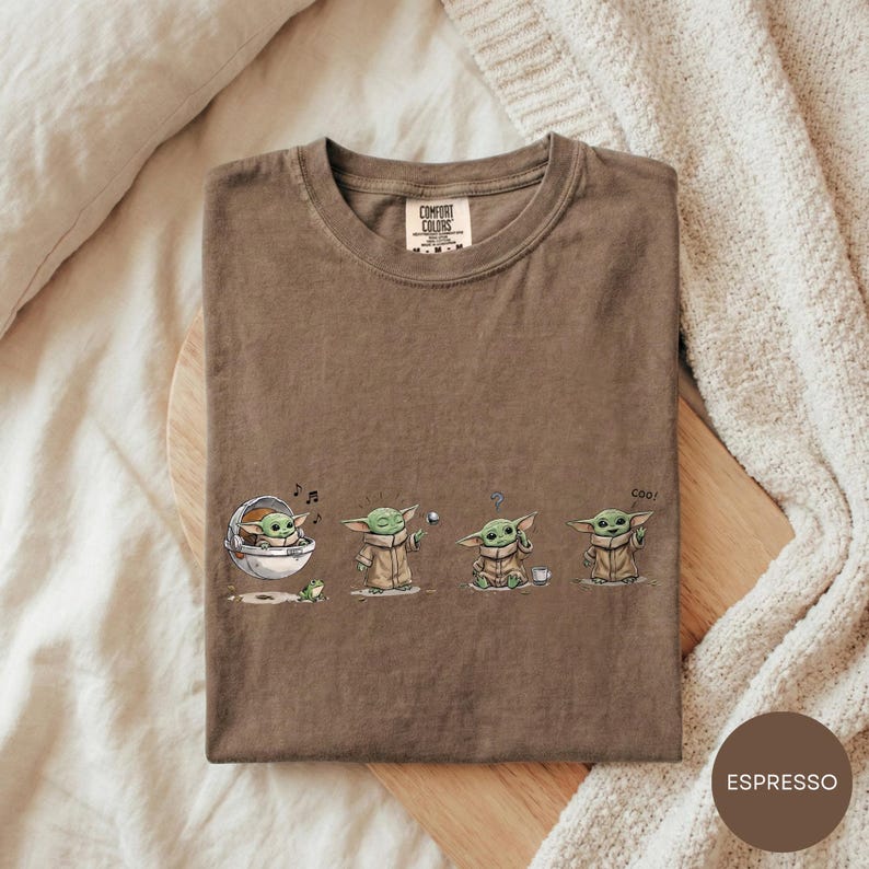A t-shirt with a graphic design featuring three baby alien characters from the Star Wars franchise, each in a different pose.