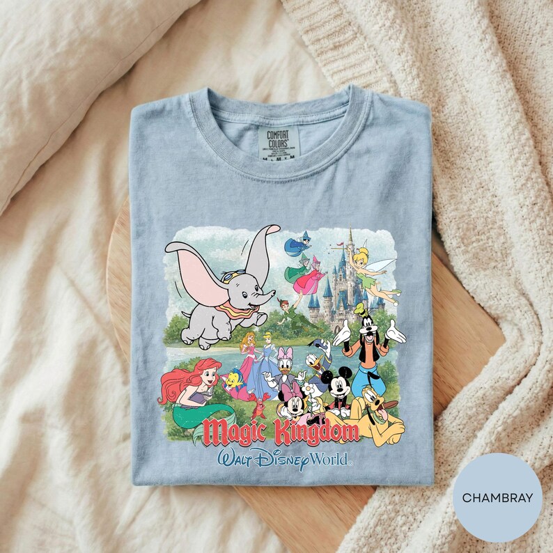 A t-shirt with a Disney-themed graphic design featuring characters from the Disney animated films, including Dumbo, Minnie Mouse, Mickey Mouse, Donald Duck, and other iconic figures.