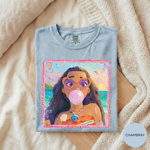 a t-shirt with a colorful illustration of a character blowing a bubble gum bubble, surrounded by various objects like seashells and a beach scene.