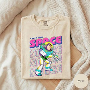A t-shirt with a colorful graphic of a character from the animated film "Toy Story" and the text "I need some SPACE" printed on it.
