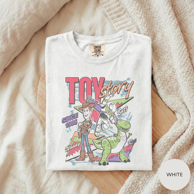 A white t-shirt with a colorful graphic design featuring characters from the Toy Story movie, including Woody and Buzz Lightyear.