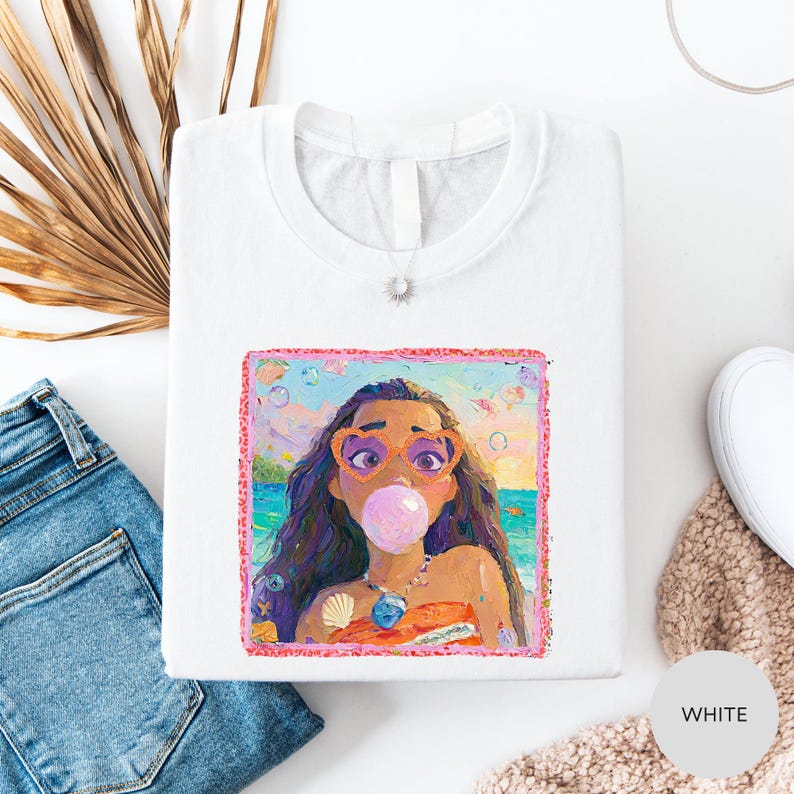 a white t-shirt with a colorful illustration of a woman blowing a bubble gum bubble, surrounded by various clothing items such as jeans and a sweater.