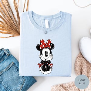 a light blue t-shirt with a Minnie Mouse graphic, a pair of blue jeans, and some beige knitted items.