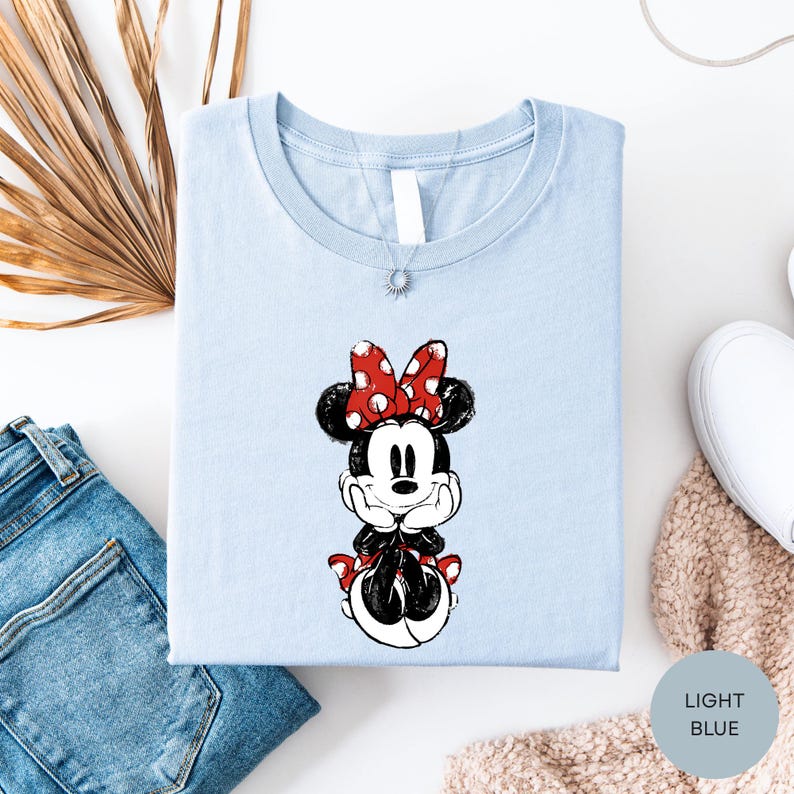 a light blue t-shirt with a Minnie Mouse graphic, a pair of blue jeans, and some beige knitted items.
